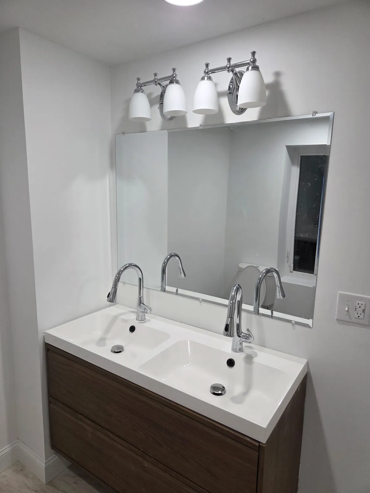 Bathroom with a double-sink floating vanity, large mirror, and four-light vanity fixture