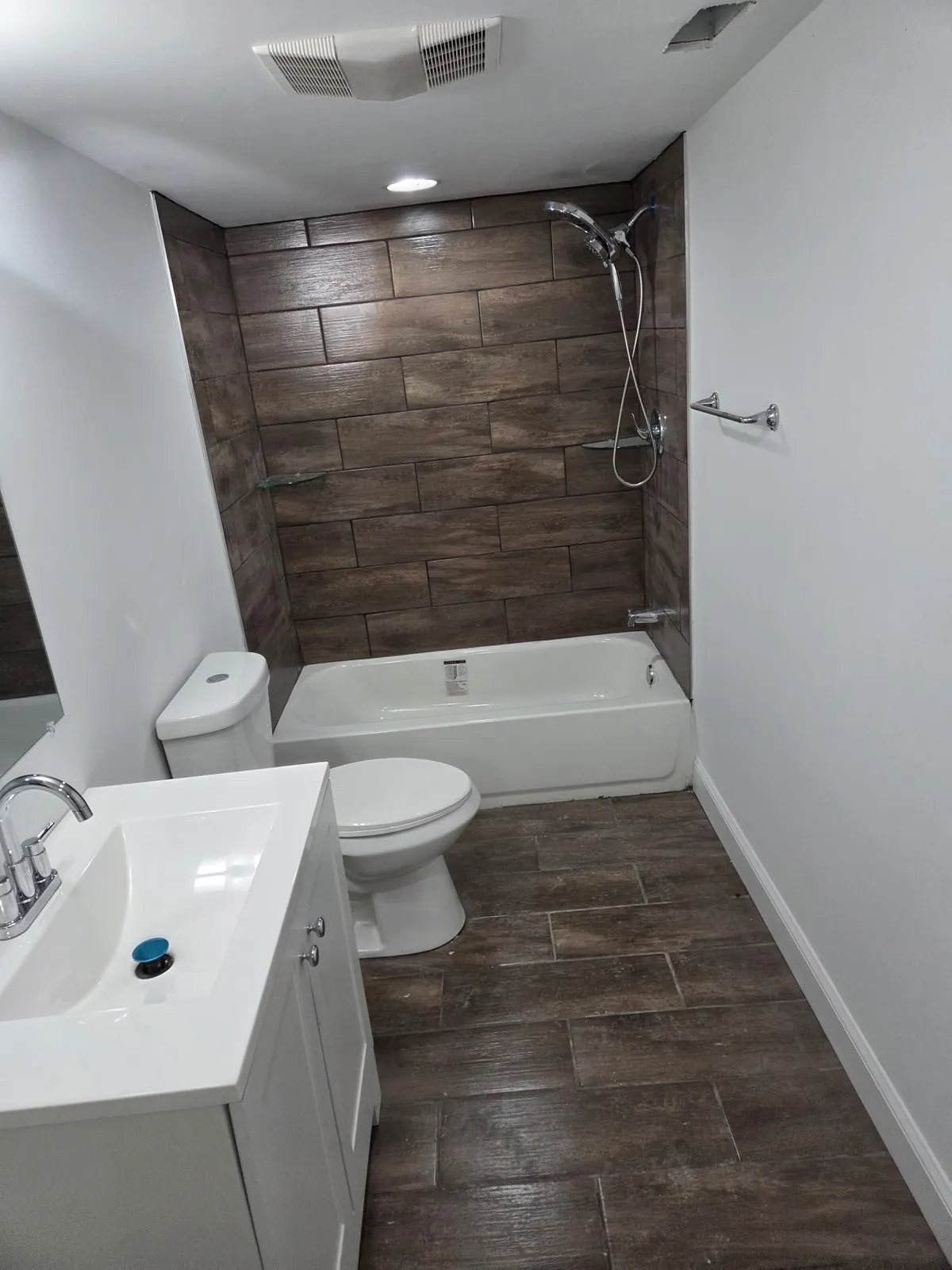 Bathroom with wood-look tile tub surround, new vanity, and tile floor