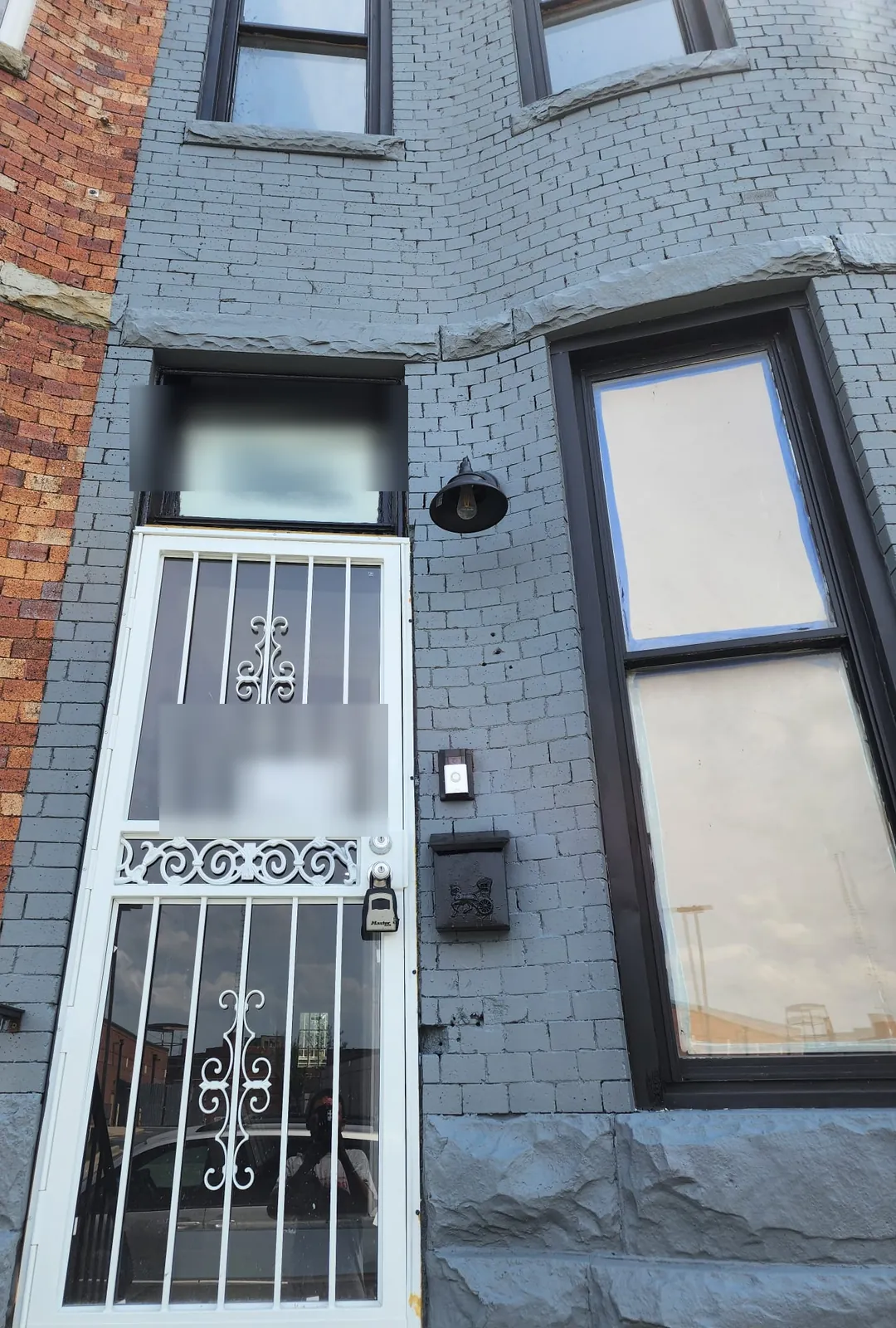 Painted brick rowhouse facade with new black-trimmed windows and a white security storm door