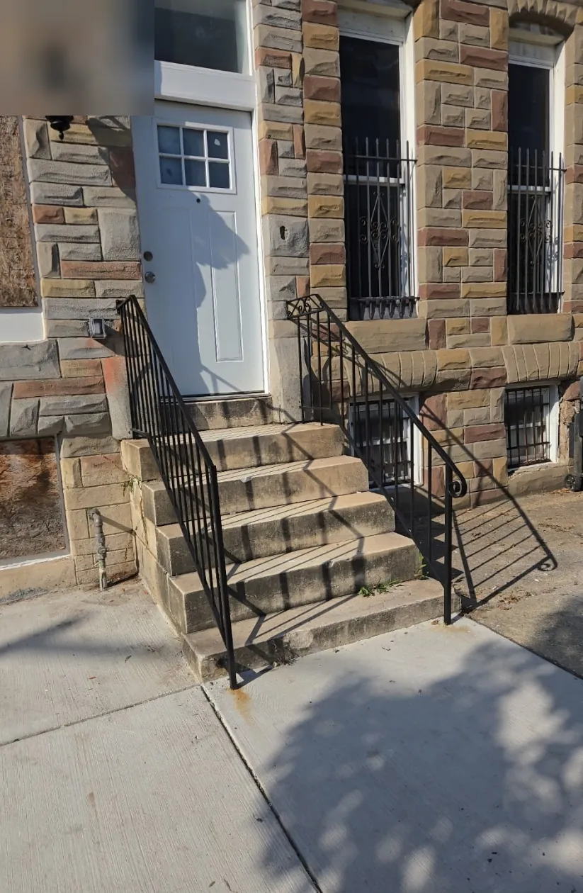 Front entry with a new door, restored stone steps, and black metal handrails
