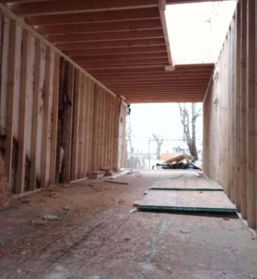 Rowhouse gutted to the shell with new ceiling framing and open walls, looking toward the rear