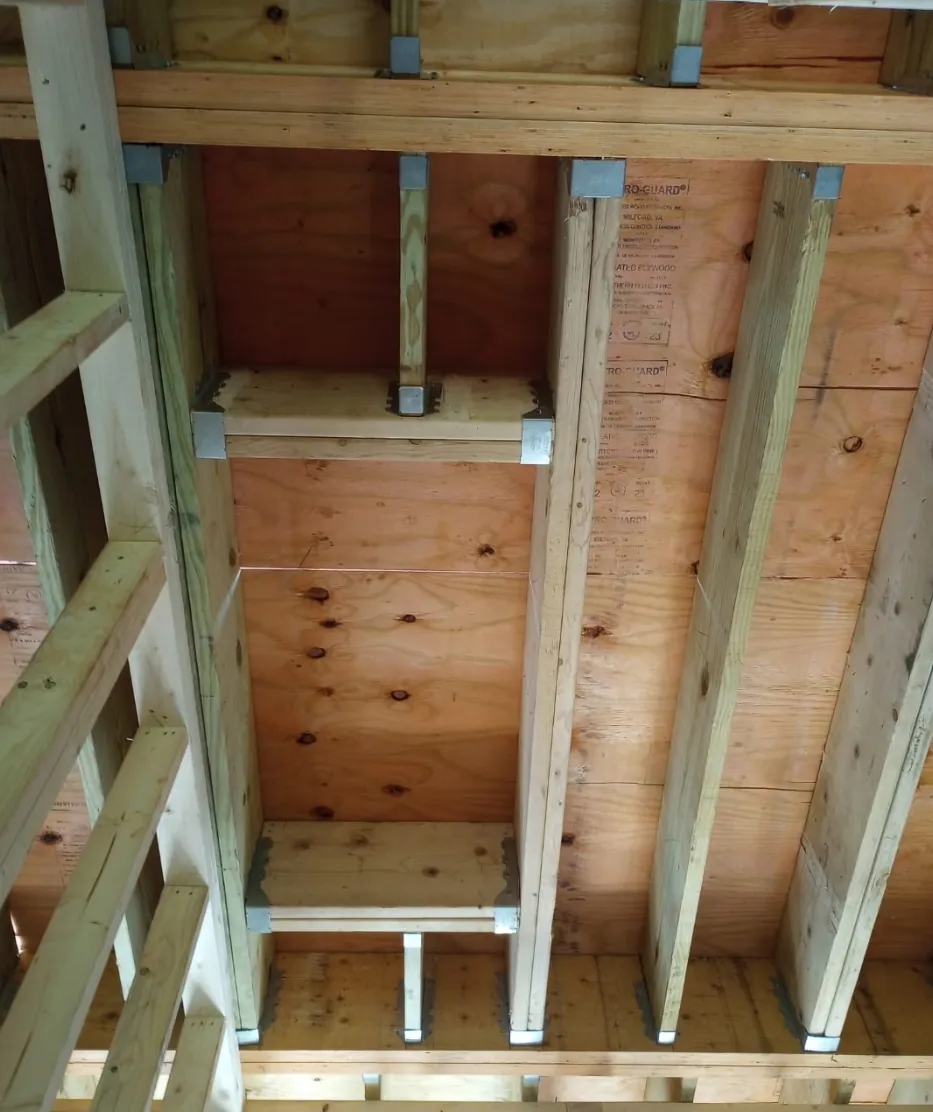 New floor joists with metal joist hangers and fresh subfloor, seen from below