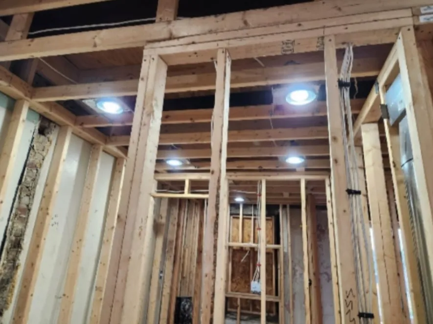 New stud walls framed for rooms, with recessed lights roughed in overhead