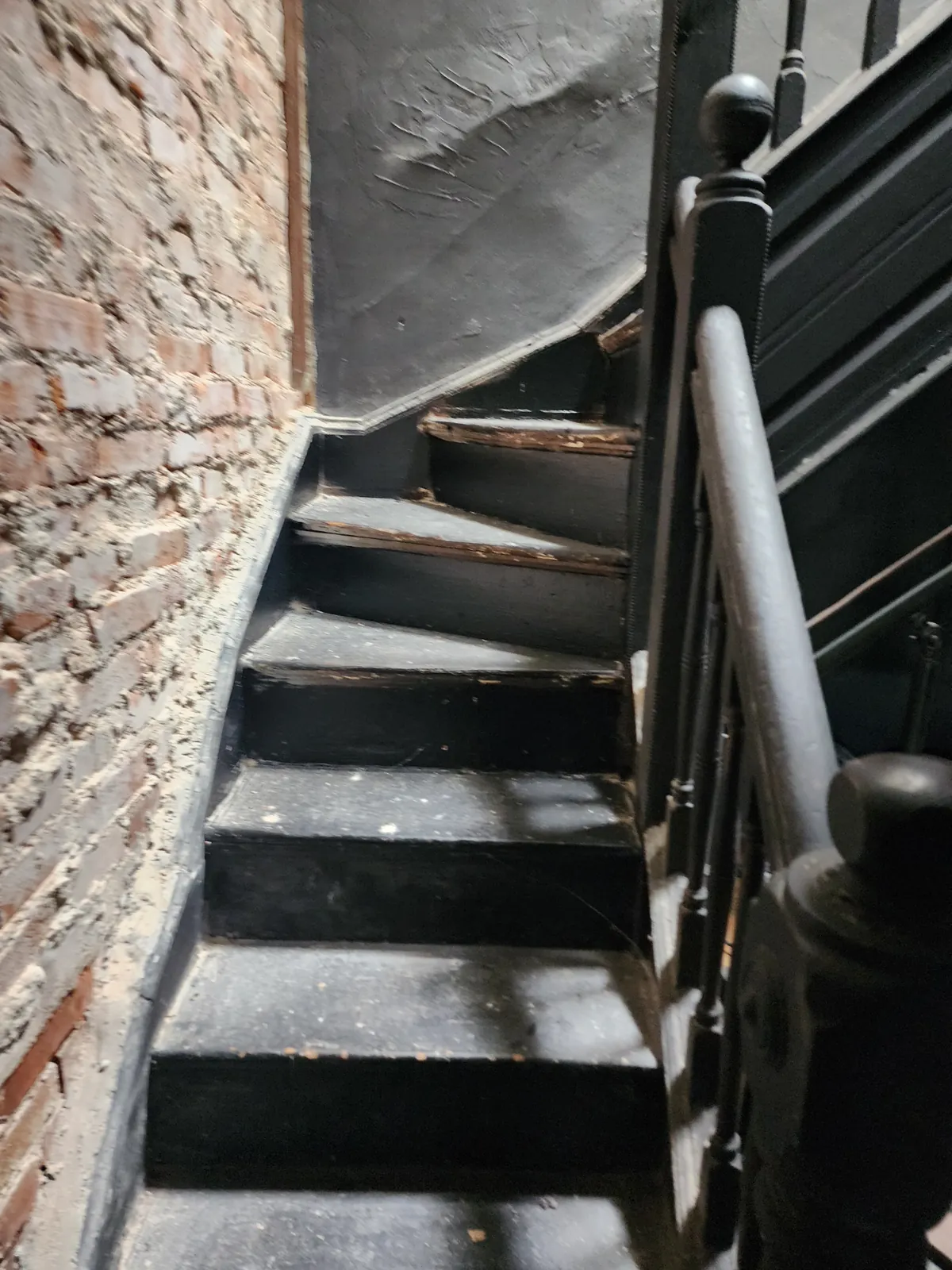Before: worn, dark staircase beside an unfinished brick wall