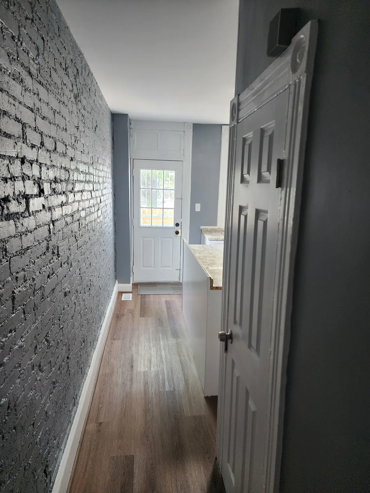 Hallway with painted exposed brick, new flooring, and fresh trim