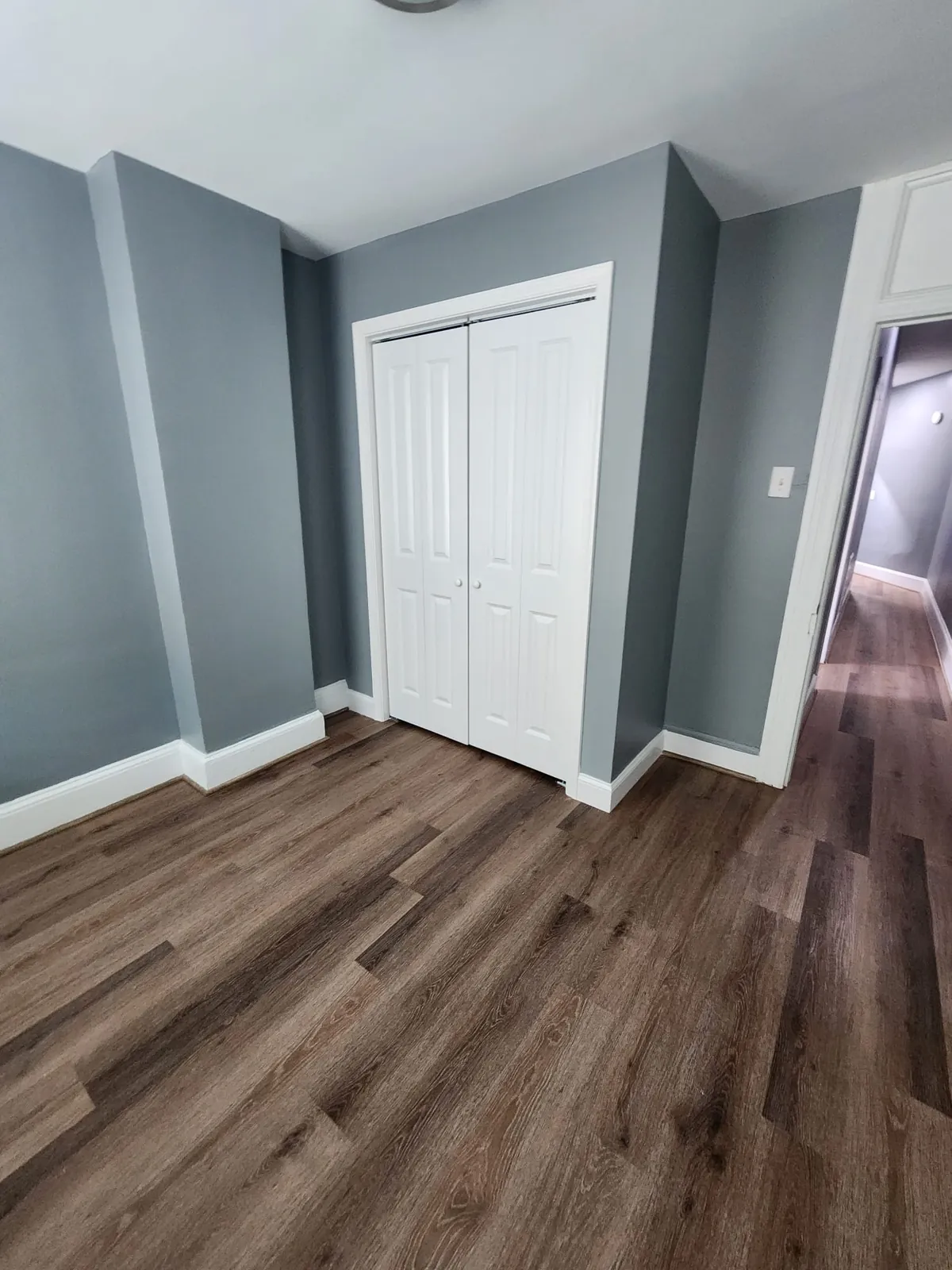 Bedroom with new plank flooring, fresh paint, and double closet doors