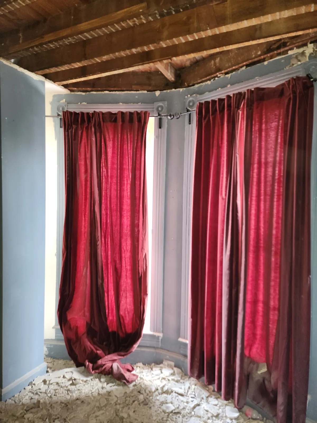 Before: bay-window room with the ceiling opened up and plaster debris on the floor