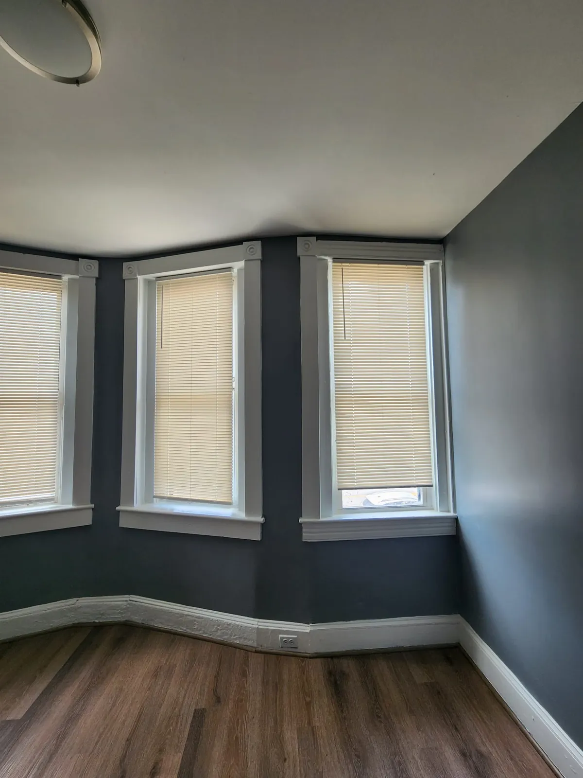 Bay-window room with new flooring, paint, and window trim