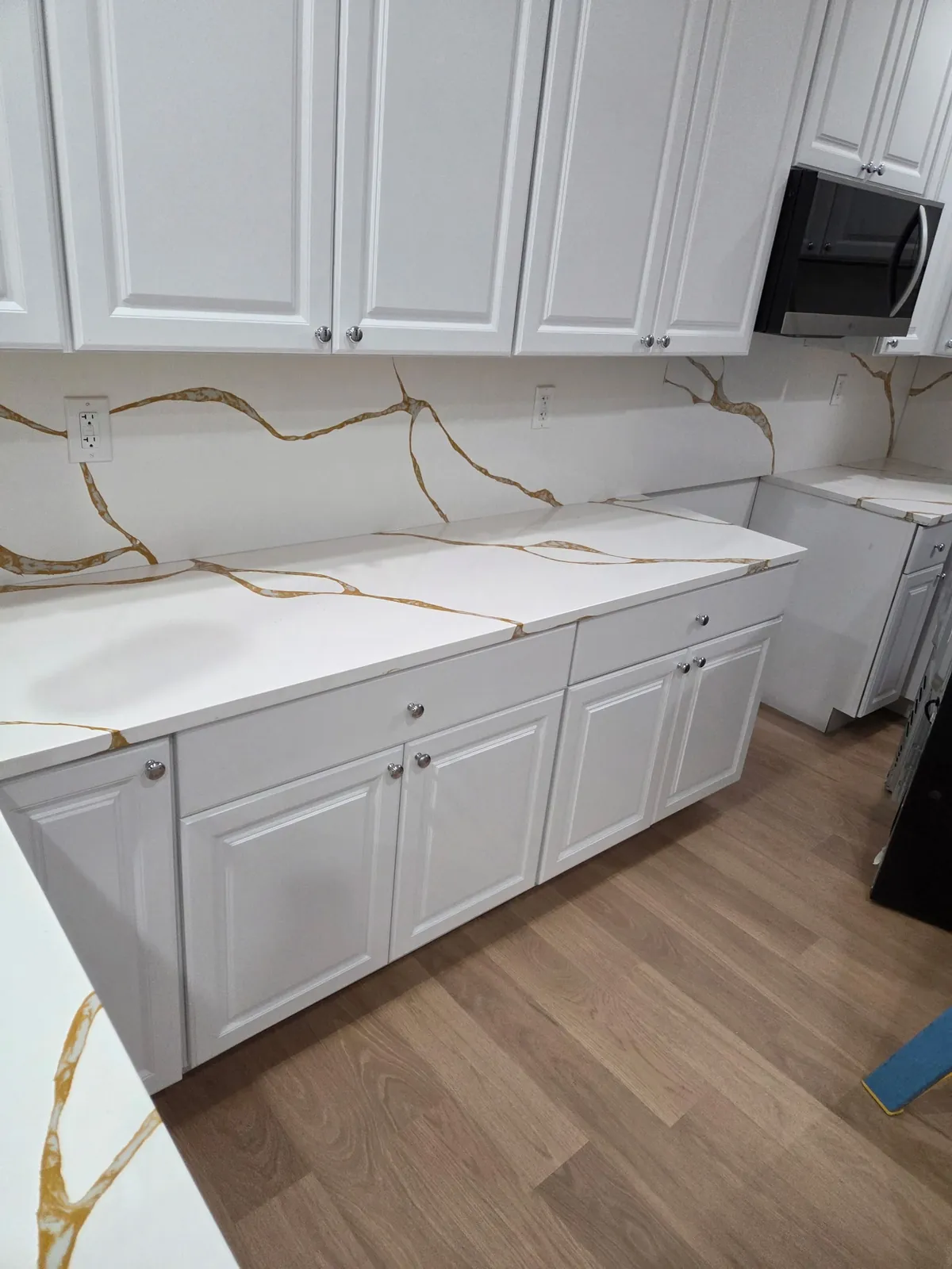 Close-up of new base cabinets and veined marble-look countertop