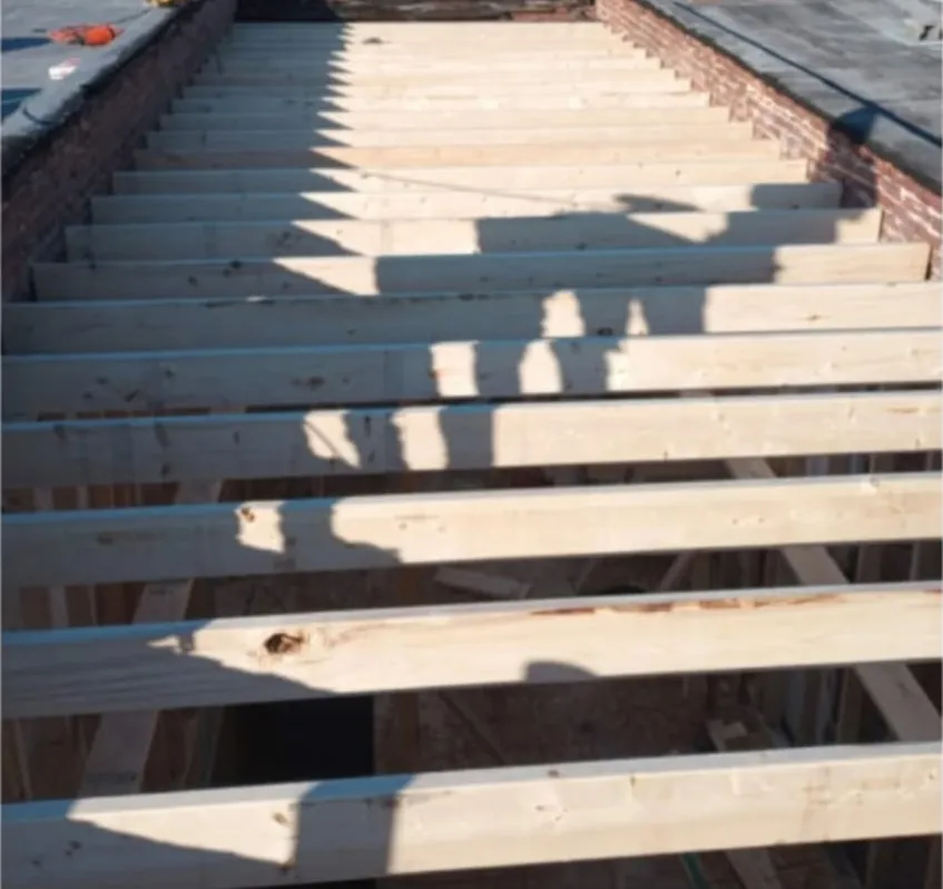 New roof joists installed between brick party walls after tear-off